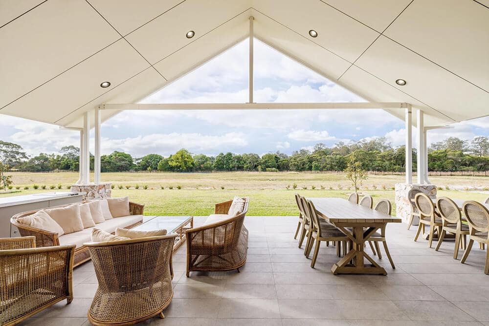 Tables and chairs set up under cover looking out at land.