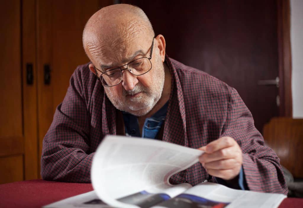 man reading statements from a magazine