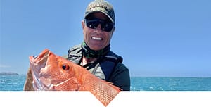 Andrew Ettingshausen on the ocean holding a large fish