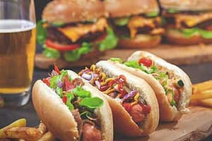 Multiple hot dogs and burgers with a beer