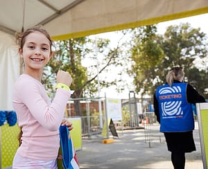 Child wearing the kids information wrist band behind OzTix worker