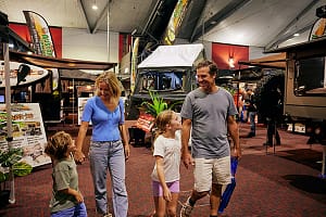 Family walking around the Caravan Camping expo past some camper trailers.
