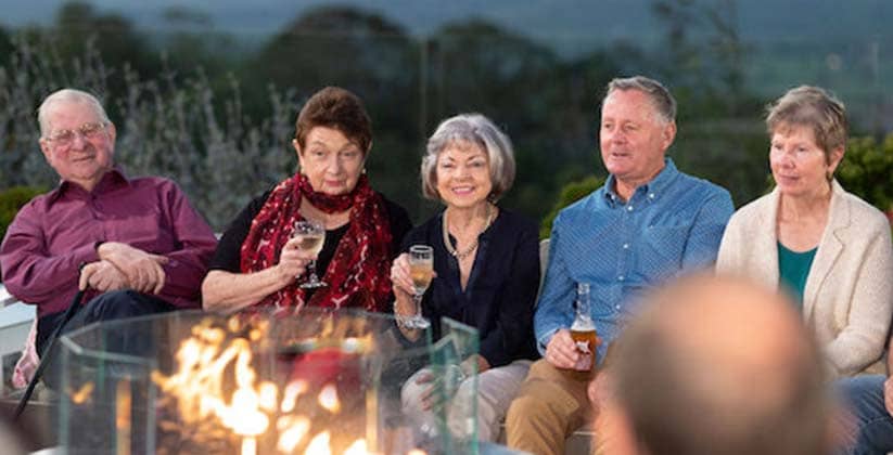 Friends sitting with each other around an enclosed fire