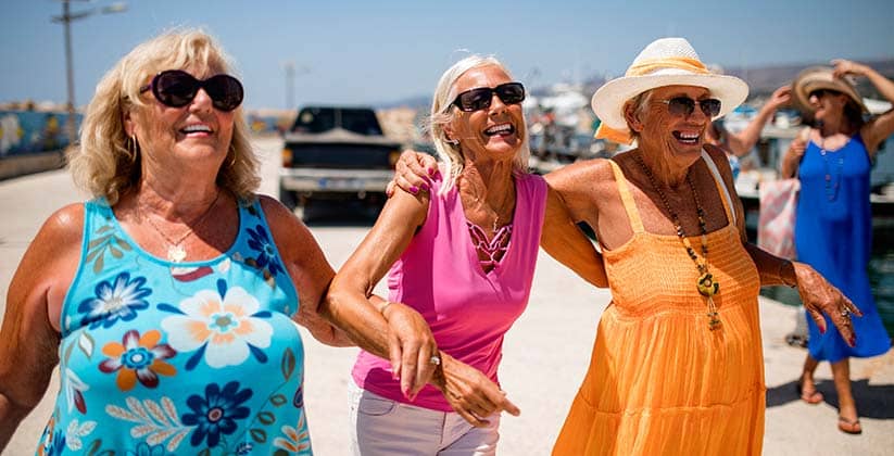 Three elderly women holding on to each other and having a good time