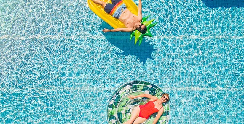 A man and women floating on crystal clear water in pool