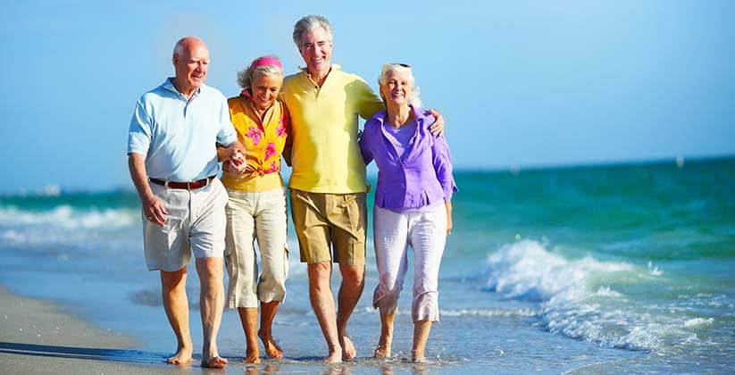Two elderly couples walking along the beach with each other